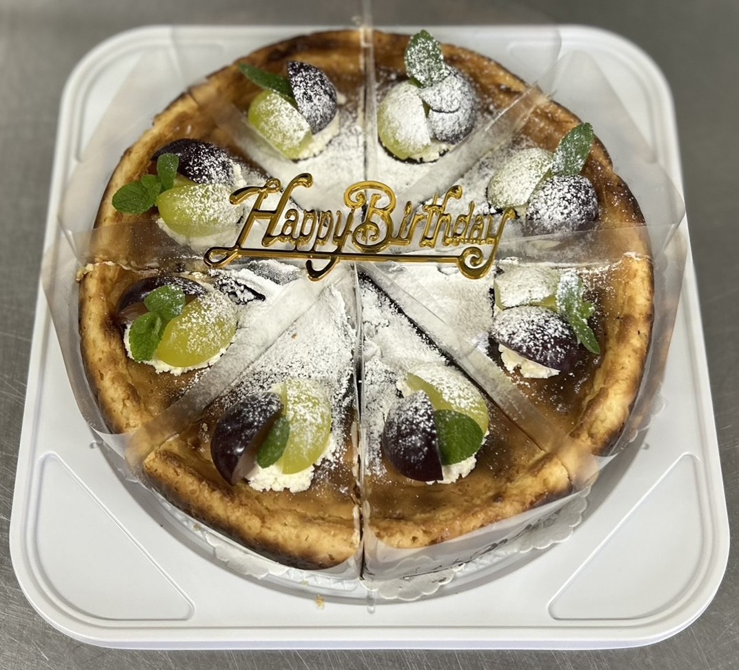 誕生日飾りとぶどうを添えて切り分けたチーズケーキ