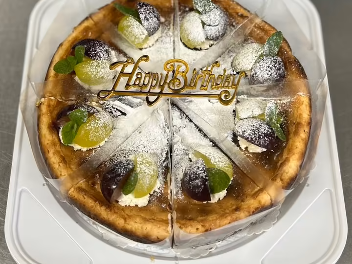 誕生日飾りとぶどうを添えて切り分けたチーズケーキ